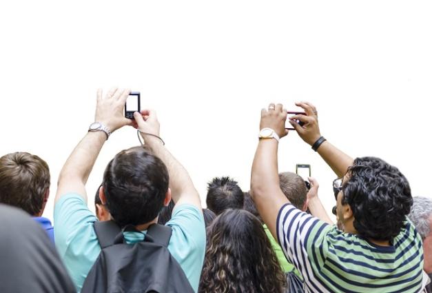 Image of a crowd of people stretching their arms in the air to take photos with their phones and cameras