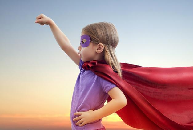 Image of young girl in a cape and mask pretending to be a superhero