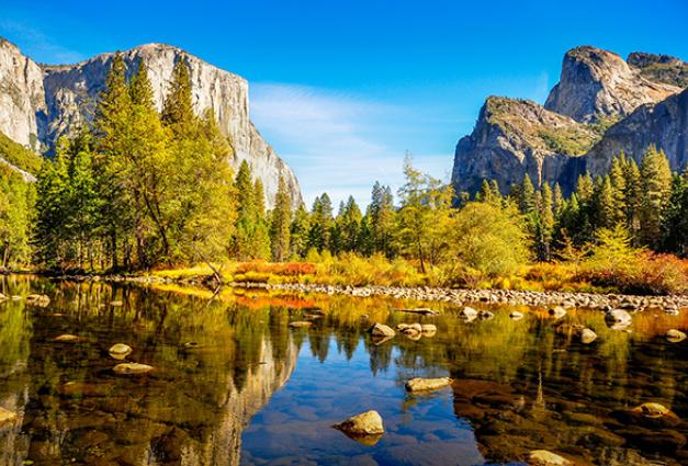 Image of beautiful green trees and mountains reflecting into calm stream