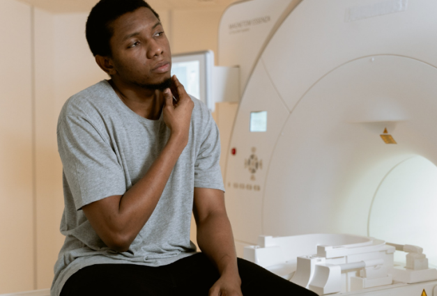 An image of a young Black man sitting in a healthcare facility.