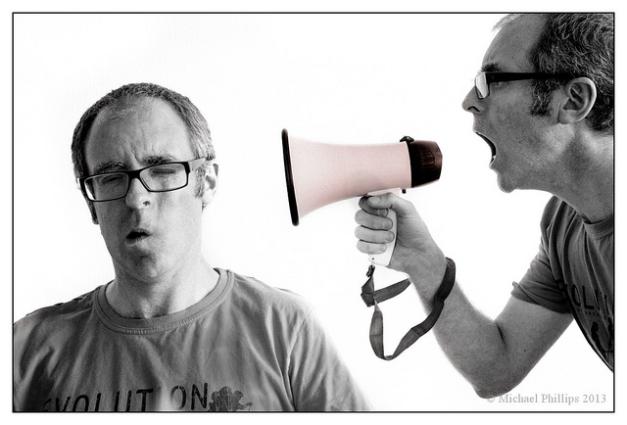 An image of a man shouting into a megaphone at another man