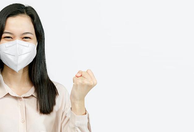 Asian woman wearing a mask raising her hands up
