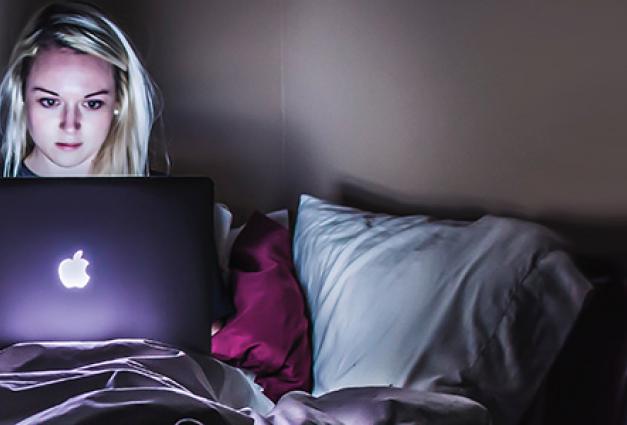 Young woman in bed on laptop