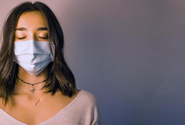 calm woman in face mask standing against dark pink wall