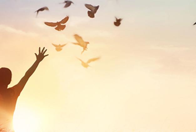 Woman with hands in air and birds flying around her