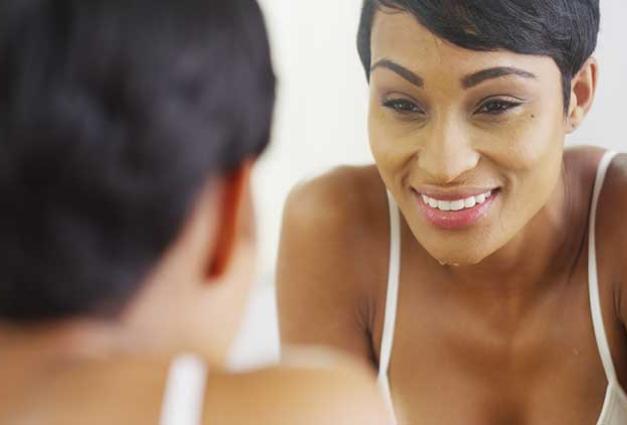 woman looking at her face in mirror, smiling