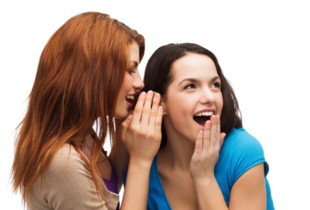 An image of two women whispering to one another