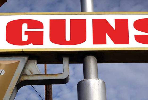 sign up high shaped like a gun with the word guns on it