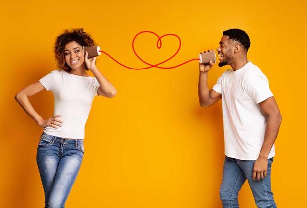 Young black couple with can phone on orange background