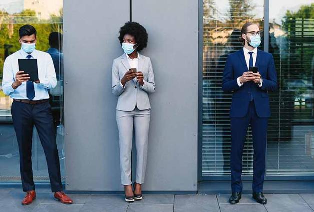 Masked Businesspeople with gadgets keeping social distance