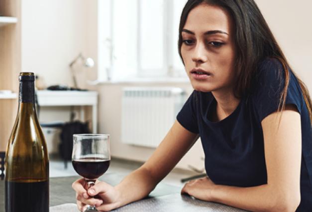 Young woman sitting in kitchen with red wine