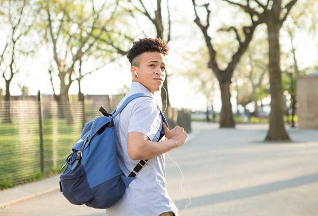 Young man looks over his shoulder as he walks across a college campus