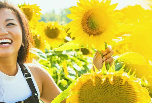 Smiling young woman surrounded by sunflowers
