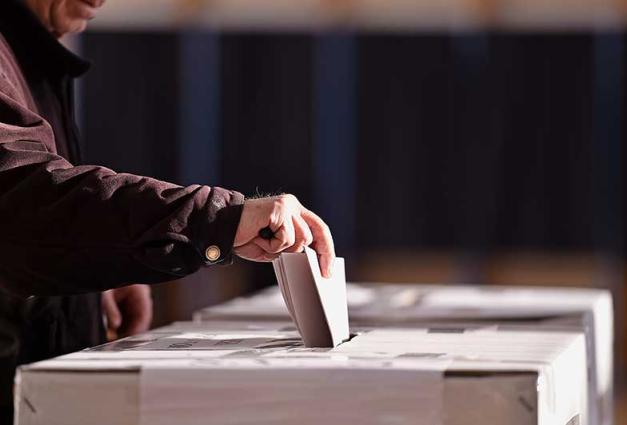 Person casting vote into ballot box