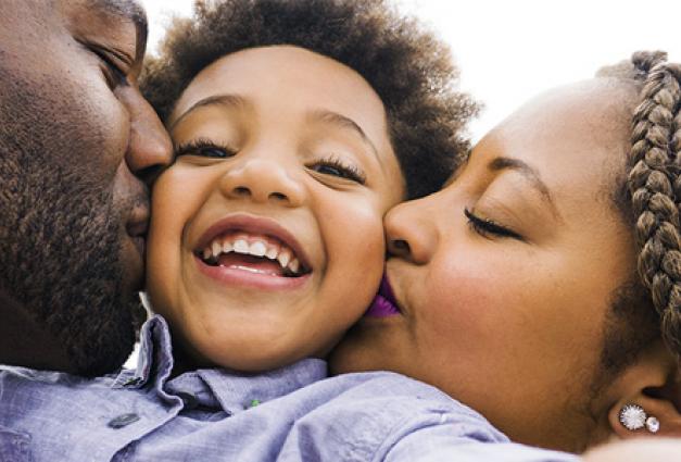 Black couple embracing and kissing young son