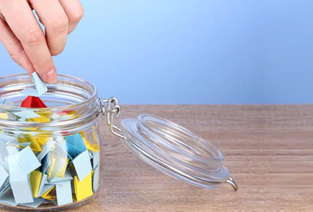 Image of a hand placing folded pieces of paper into a jar