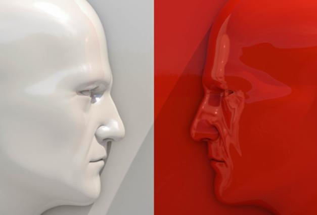 Image of two opposing face statues, the left is white the right is red