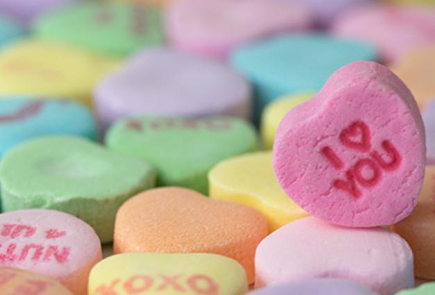 Candy hearts cover the image, with one standing up with I heart you stamped on the front.