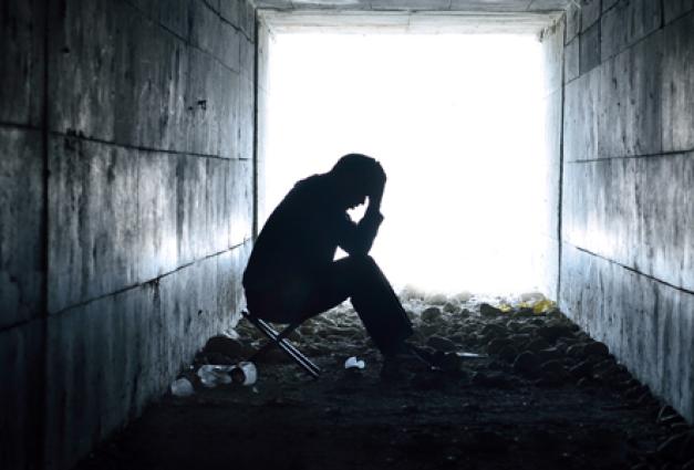 Photo of a depressed man sitting in a tunnel